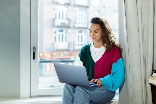 Woman working on a laptop on a window sill